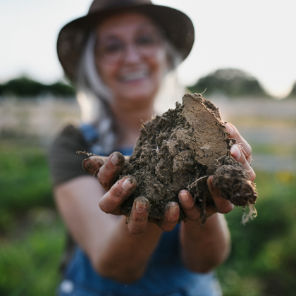 A farmer holding healthy, nutrient-rich soil, symbolizing Soileos’ support for regenerative agriculture practices that build soil health, increase resilience, and reduce environmental impacts.